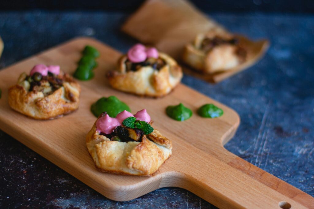 Mouth-watering baked pastries with colorful toppings on a wooden cutting board, perfect for appetizers or snacks.